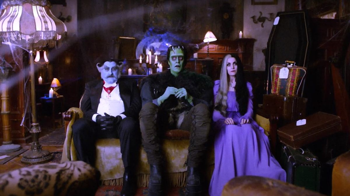 Herman, Lily and Grandpa Munster sitting on the couch in The Munsters