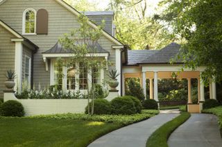 An example of front yard landscaping ideas showing a manicured lawn and concrete driveway way leading up to a covered entrance