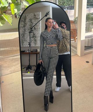 Nicola Peltz Beckham taking a selfie with smartphone in a black arched full-length mirror