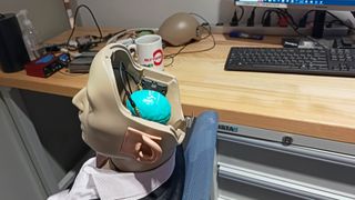 A dummy with realistic ears but an open top of the head, with electronics inside connecting to the ears