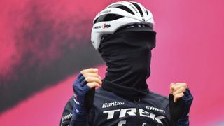 A cyclist stood on a stage wearing a buff over their whole face