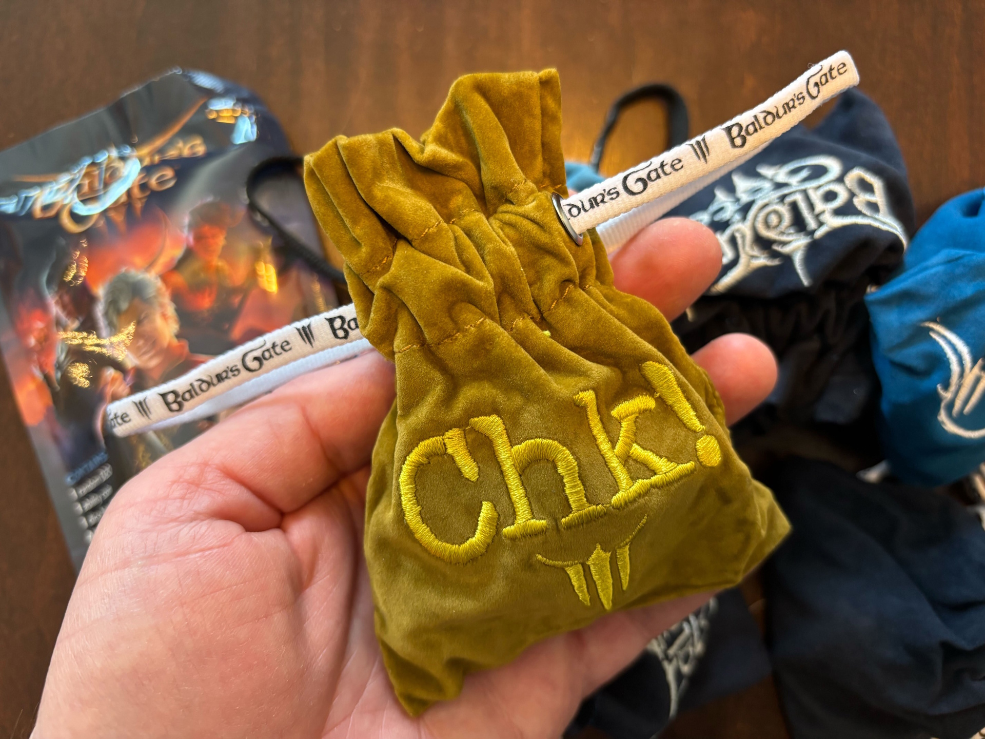 Baldur's Gate 3 Treasure Pack photo of opened dice packs with a Chk! brown bag in front