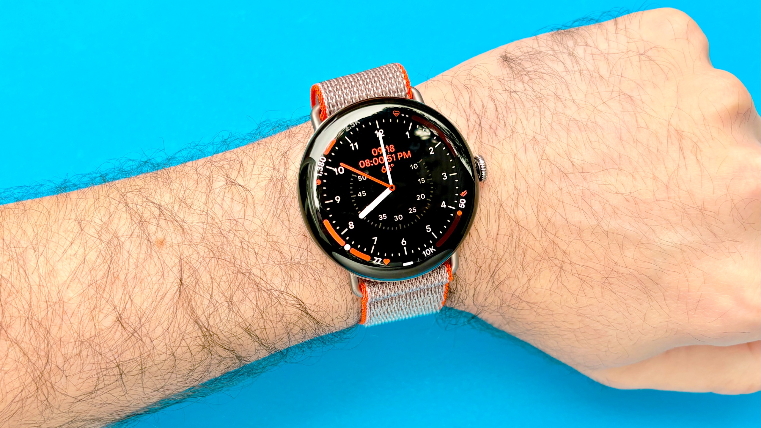 Close-up of the Pixel Watch 5 Stephen Curry edition on a user's wrist against a bright blue background
