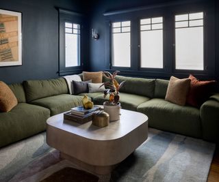 snug living room with dark blue walls and green sectional