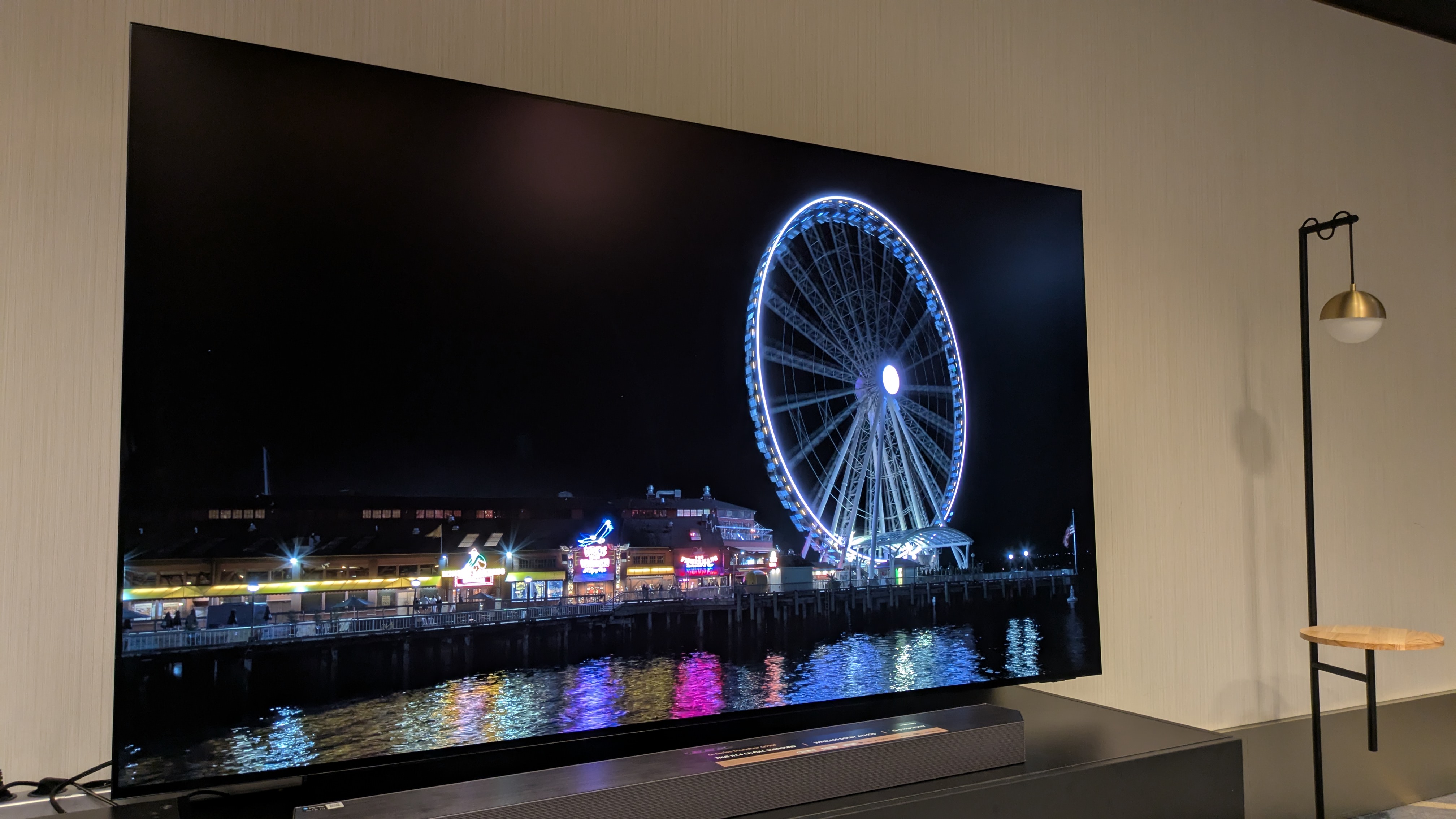 The Samsung S95F TV showing a night scene, with two very dim reflections visible in the darkness