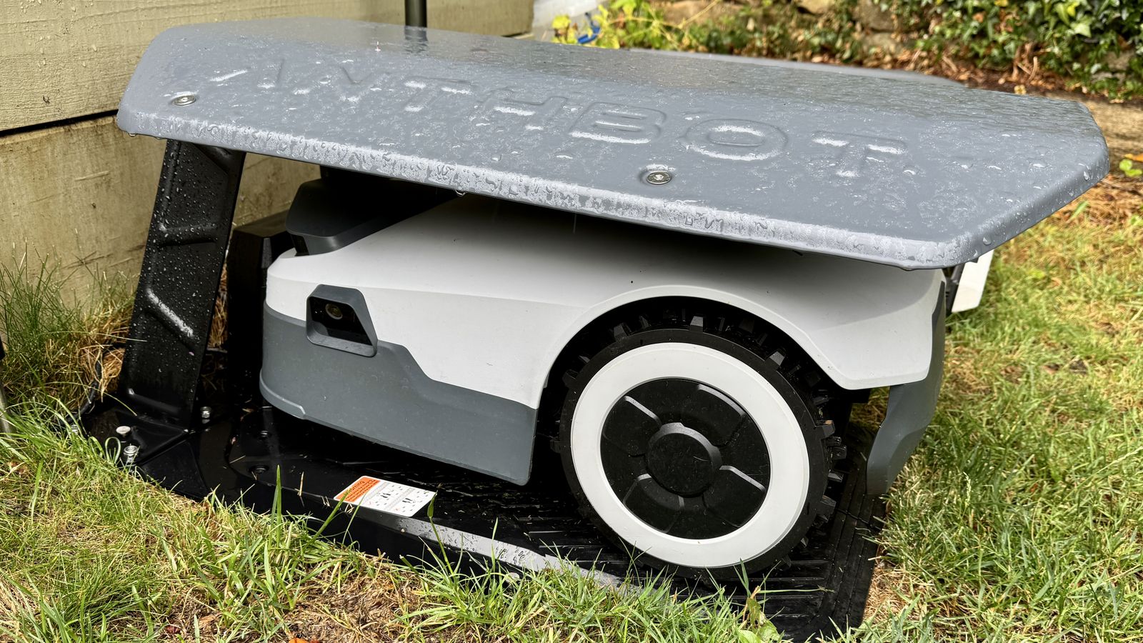 Anthbot Genie 300 robot lawn mower under cover on its charge station