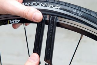 fix a puncture or repair an inner tube image shows two hands holding tyre leavers levering a tyre off a rim of a bike