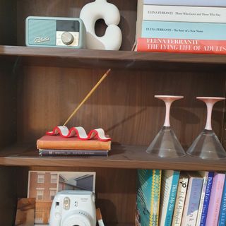 A bookcase with books and decor and an incense holder made from air dry clay with a lit incense stick