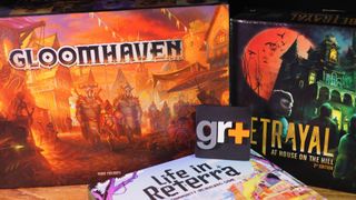 Gloomhaven, Betrayal at House on the Hill, and Life in Reterra boxes on a wooden table, with a GR+ logo sat between them