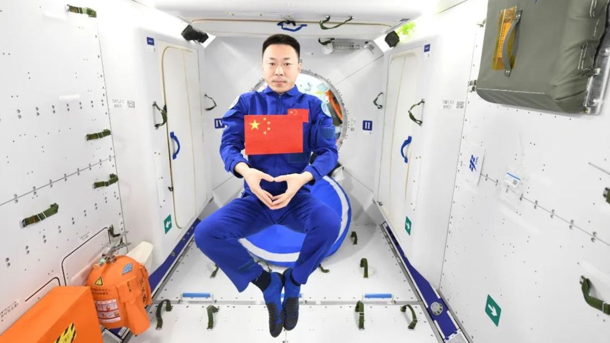 Astronaut Cai Xuzhe posing with a Chinese flag aboard the Tiangong space station.