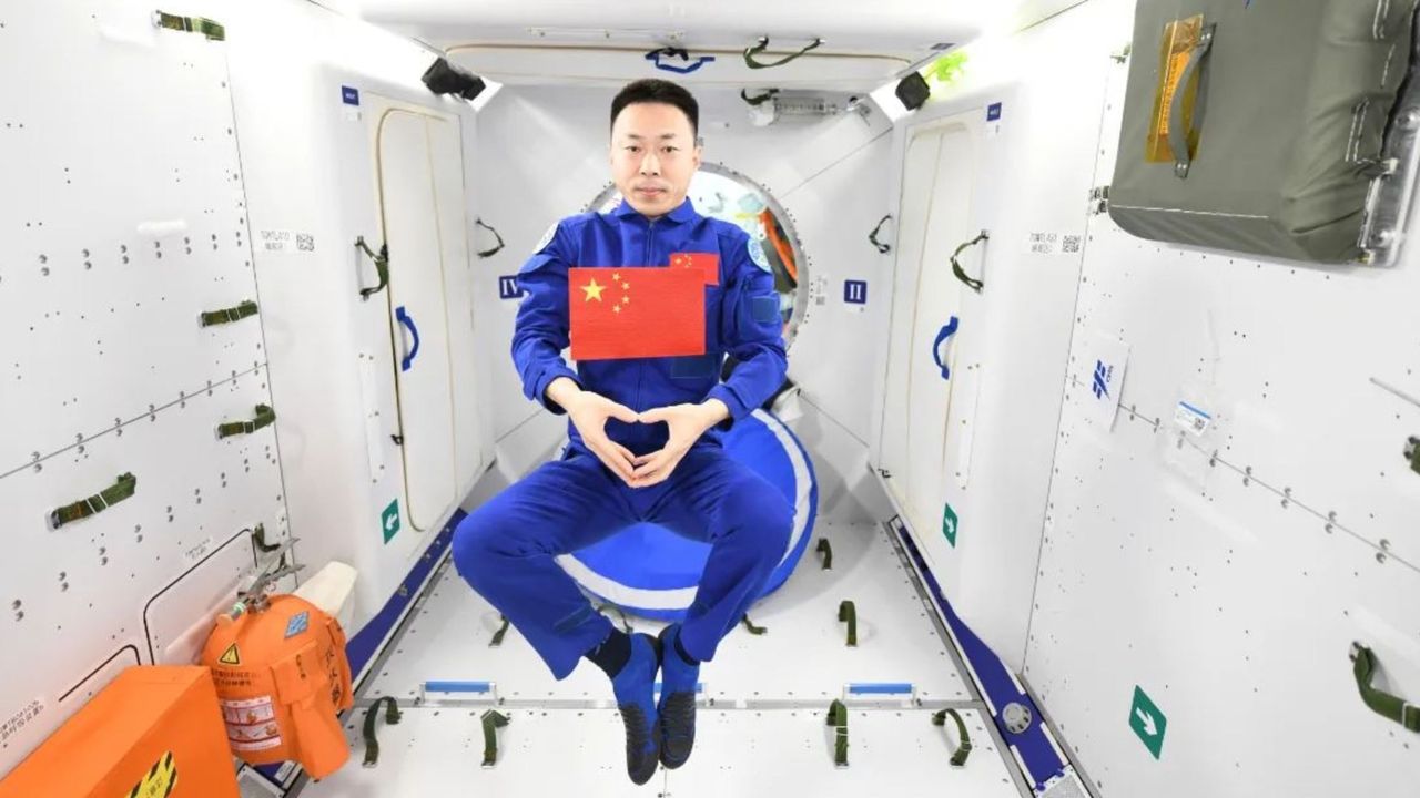 Astronaut Cai Xuzhe posing with a Chinese flag aboard the Tiangong space station.