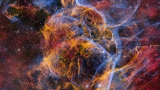 A beautiful, multicolored, textured view of various tendrils of gas forming a bubble-shape in the center of the image.