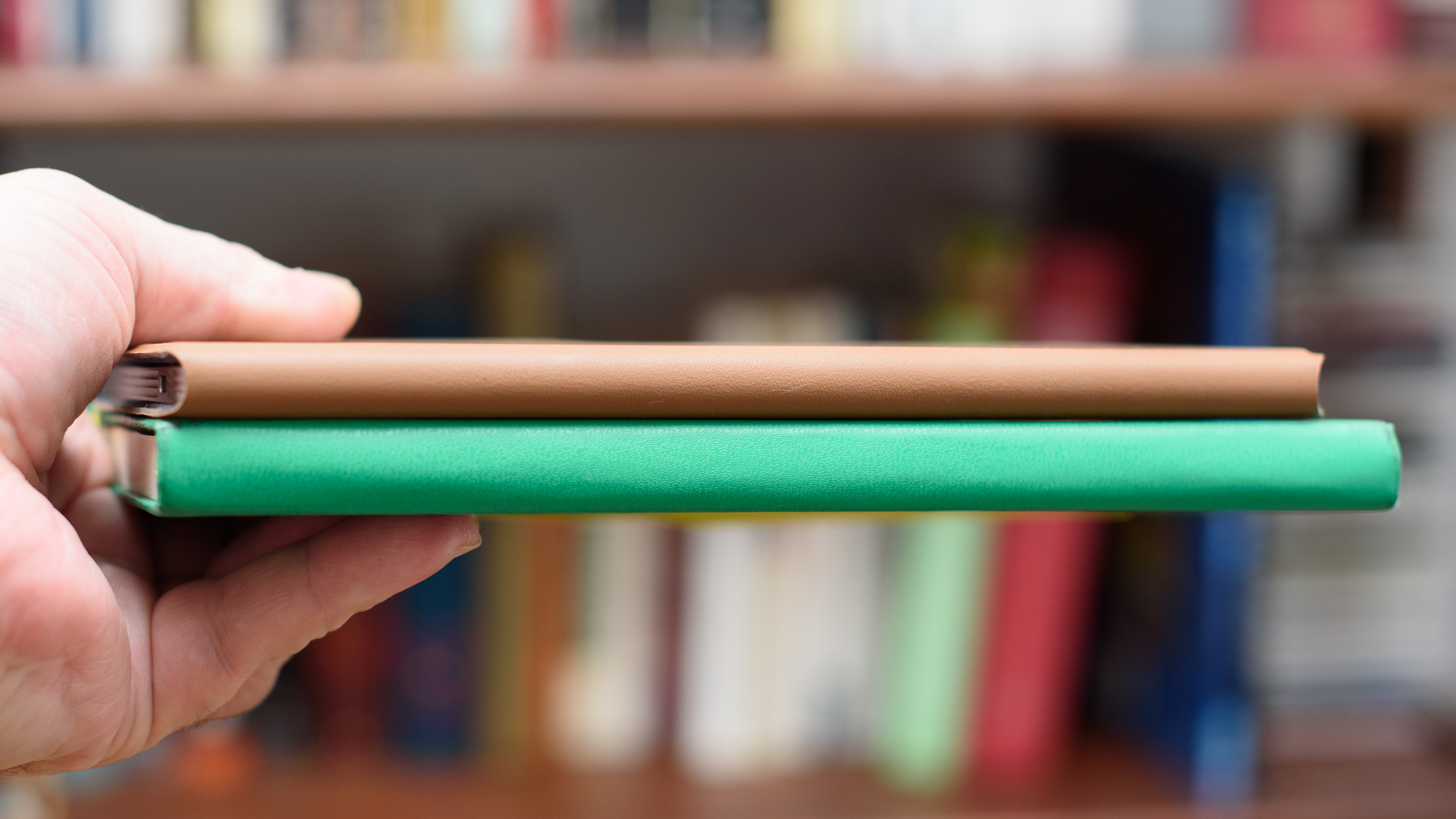 reMarkable Paper Pro Move tablet in front of a library of books, showing various writing screens and comparing the size to a Moleskine notebook