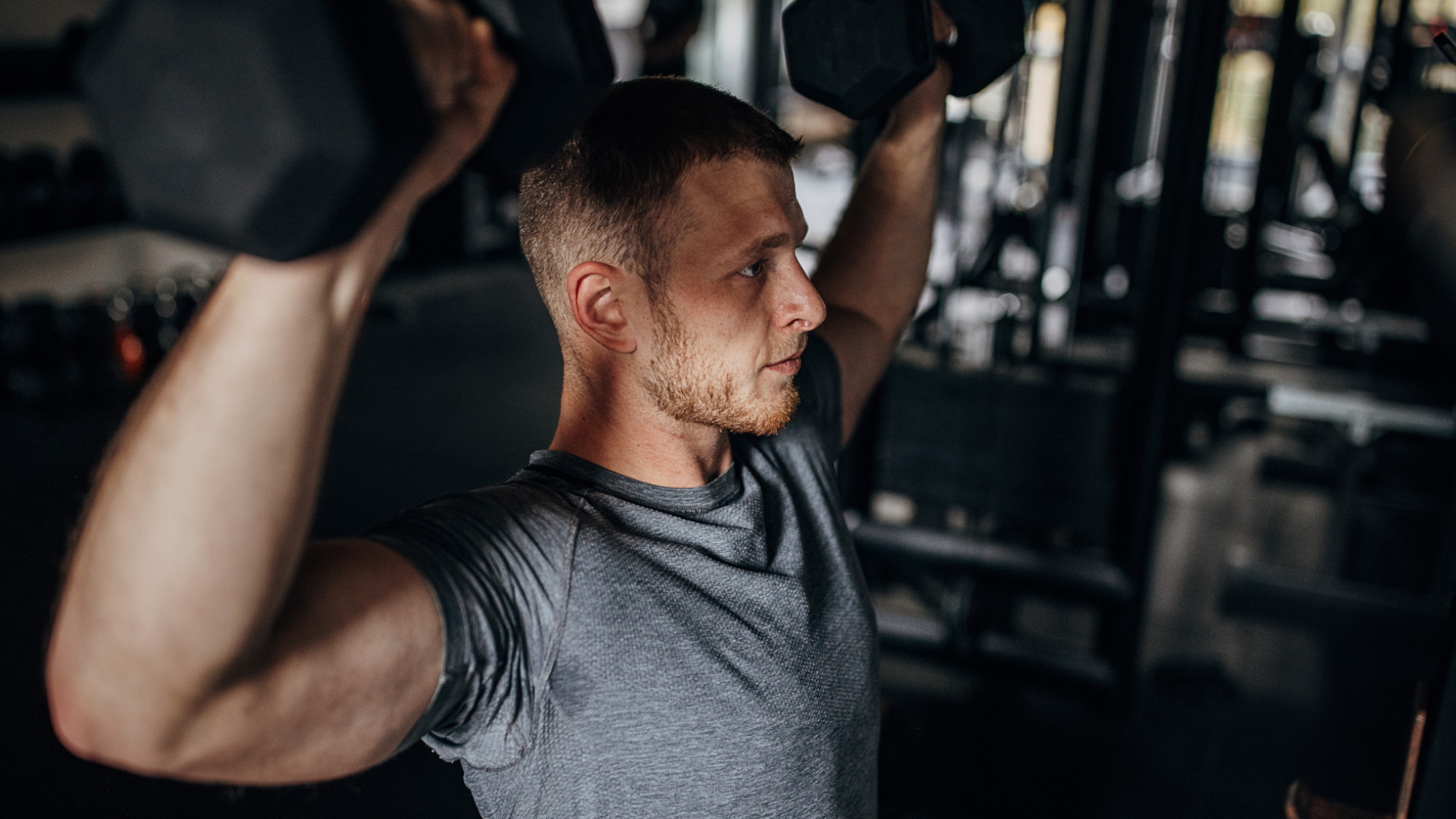 A man performing dumbbell shoulder press at the gym
