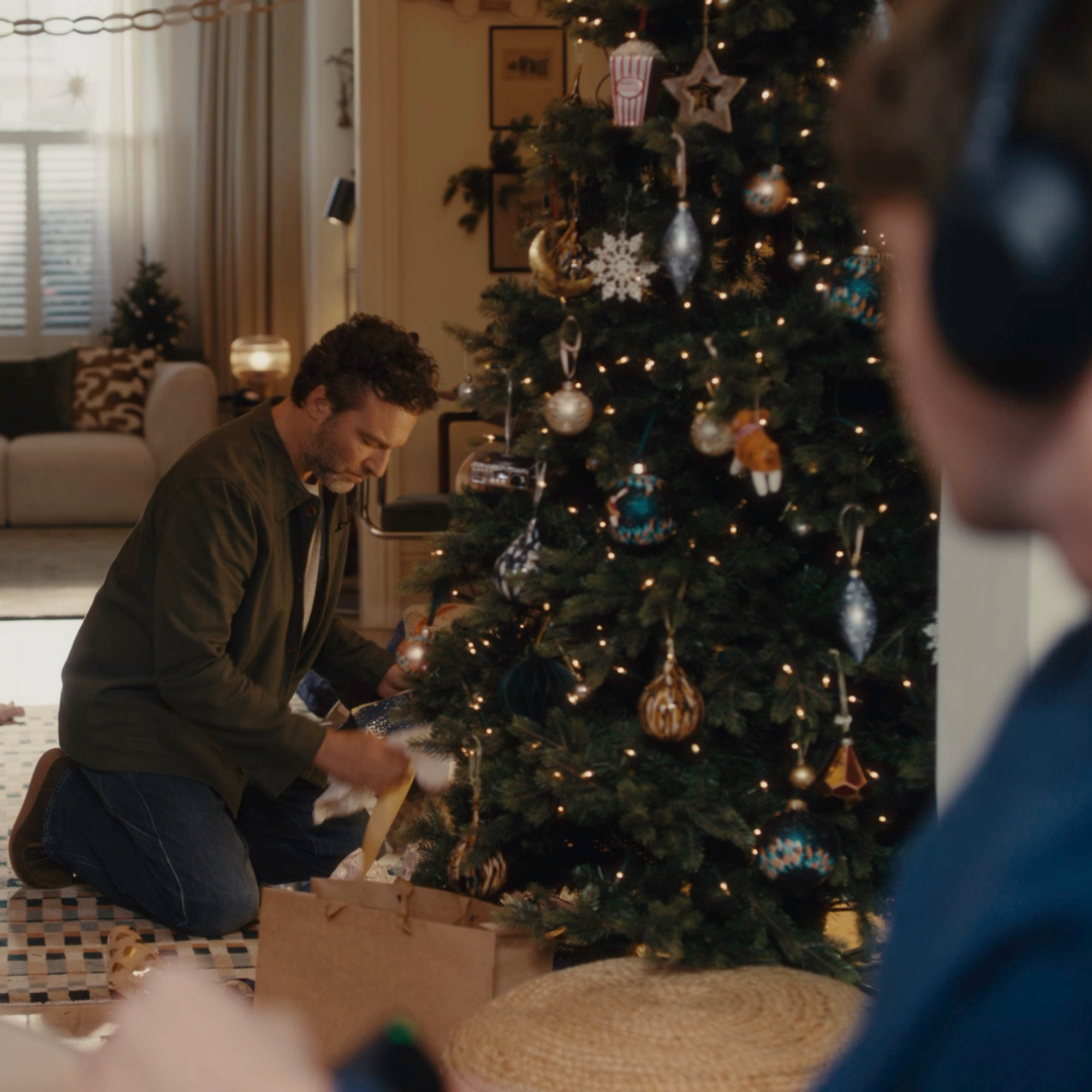 Still from 2025 John Lewis Christmas advert. It shows the dad opening his vinyl present under the tree.