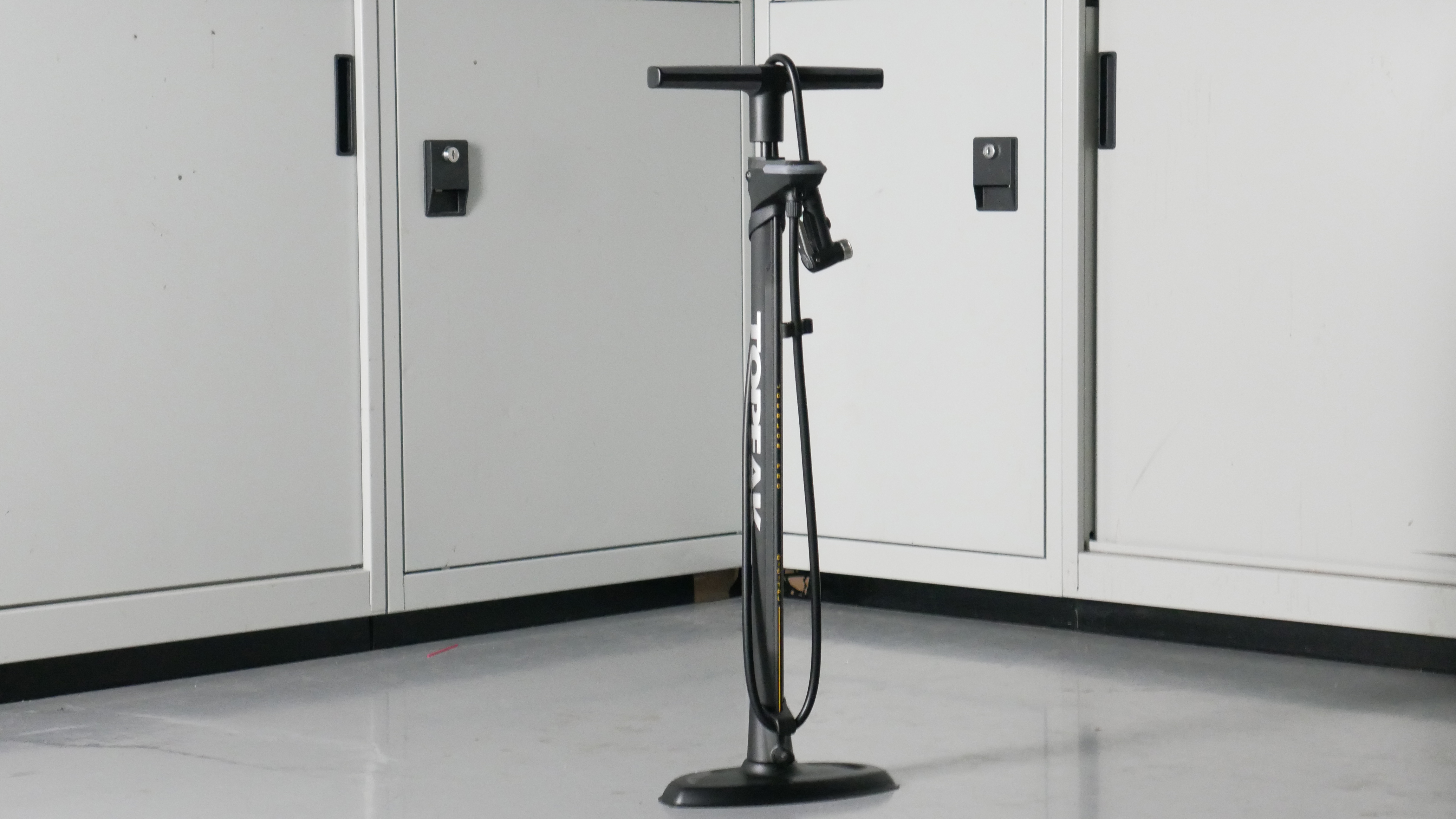 Topeak Joe Blow digital bike track pump in dark grey set to a background of some workshop cabinets