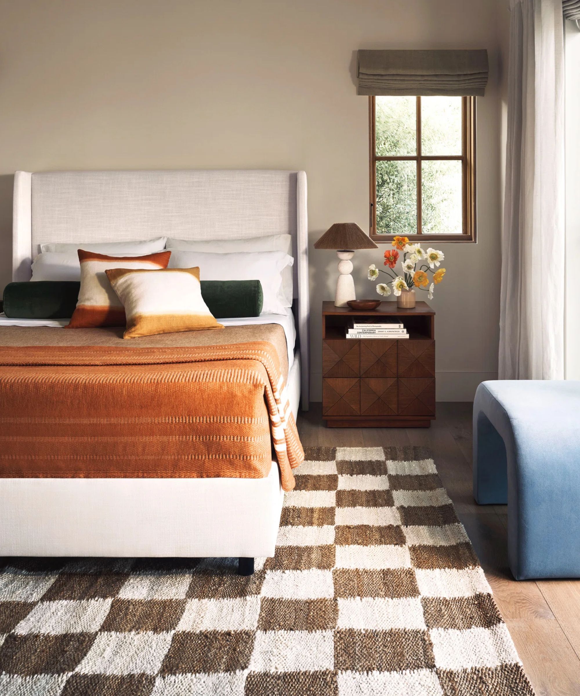 neutral bedroom with linen upholstered bed, checkerboard rug and light blue velvet bench