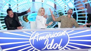 Lionel Richie Katy Perry and Luke Bryan praising a contestant from behind the desk on American Idol