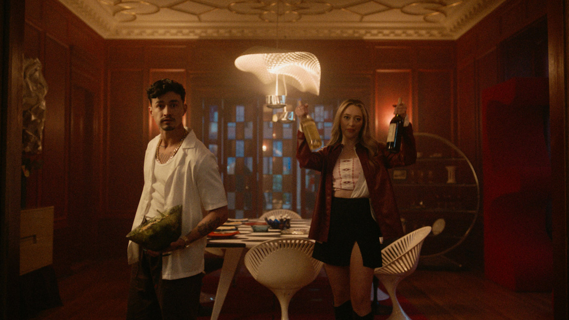 A man holds up a salad bowl subsequent to a girl who's keeping wine