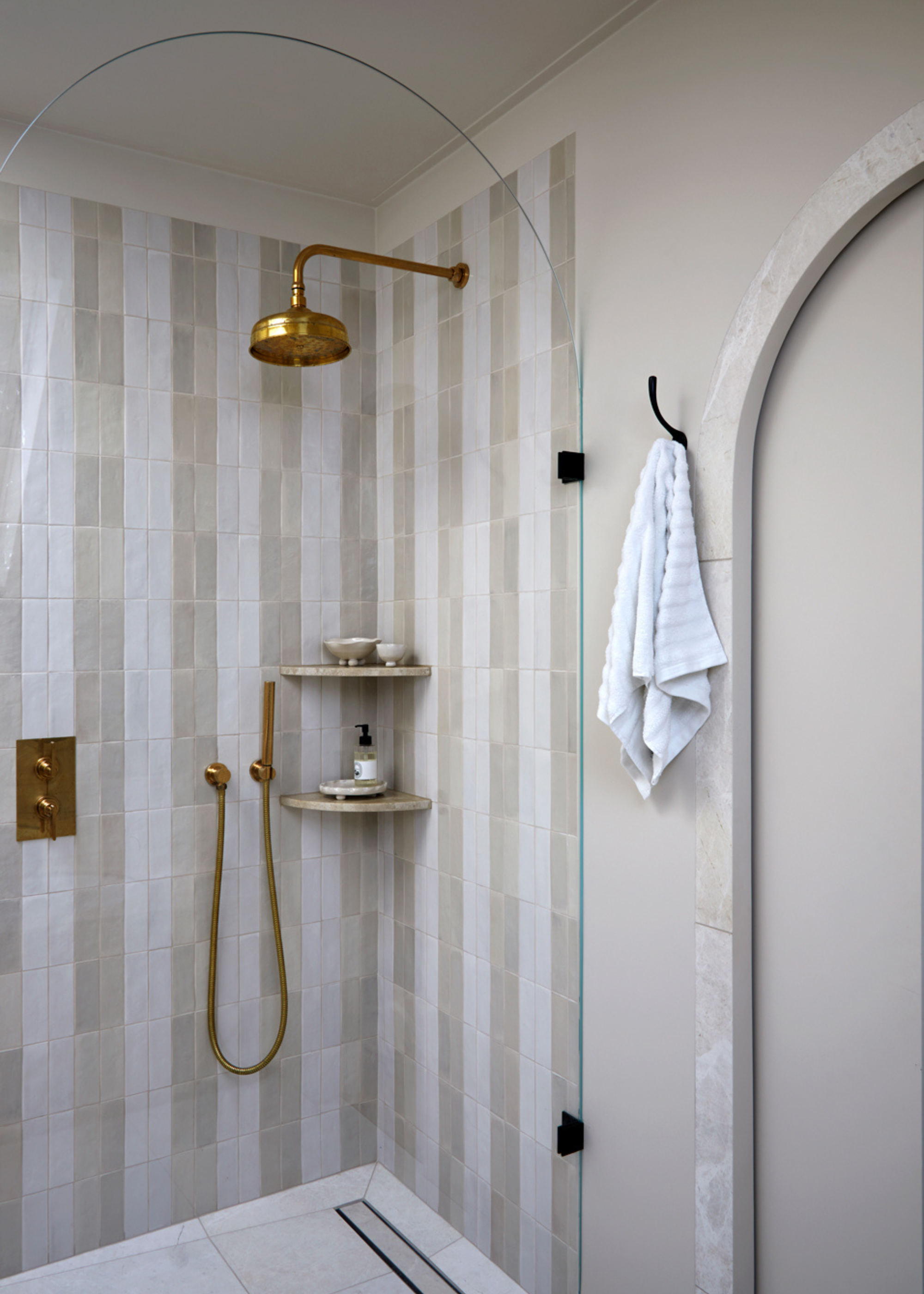 a neutral striped tile shower with brassware in a cashmere greige bathroom