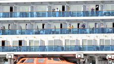 People look out from aboard the Grand Princess cruise ship, operated by Princess Cruises, as it maintains a holding pattern off the coast of San Francisco, California, on March 8, 2020.