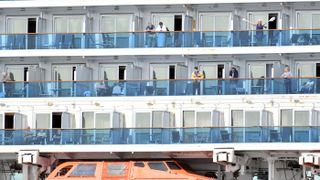 People look out from aboard the Grand Princess cruise ship, operated by Princess Cruises, as it maintains a holding pattern off the coast of San Francisco, California, on March 8, 2020.