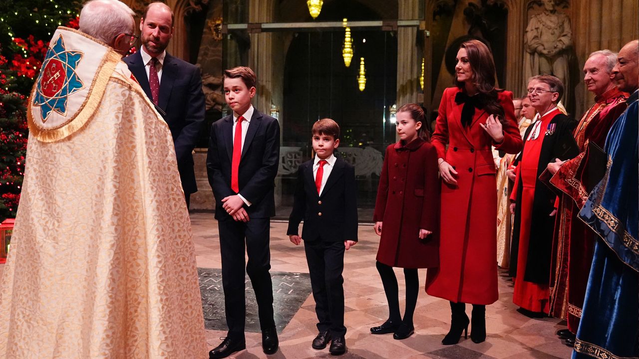 Prince William, Prince George, Prince Louis, Princess Charlotte, Kate Middleton wearing red dress coats and suits talking to a minister at Westminster Abbey