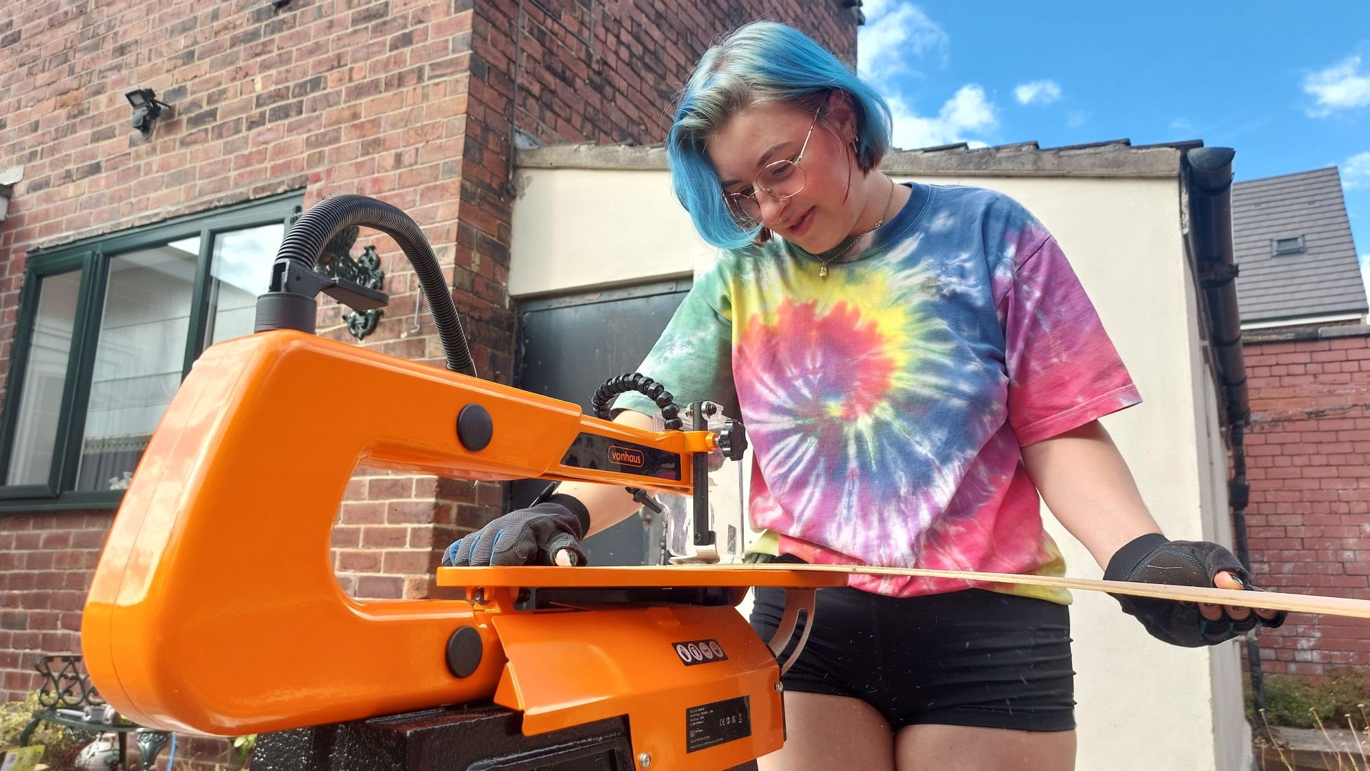 A female DIYer using a scroll saw to cut a piece of wood
