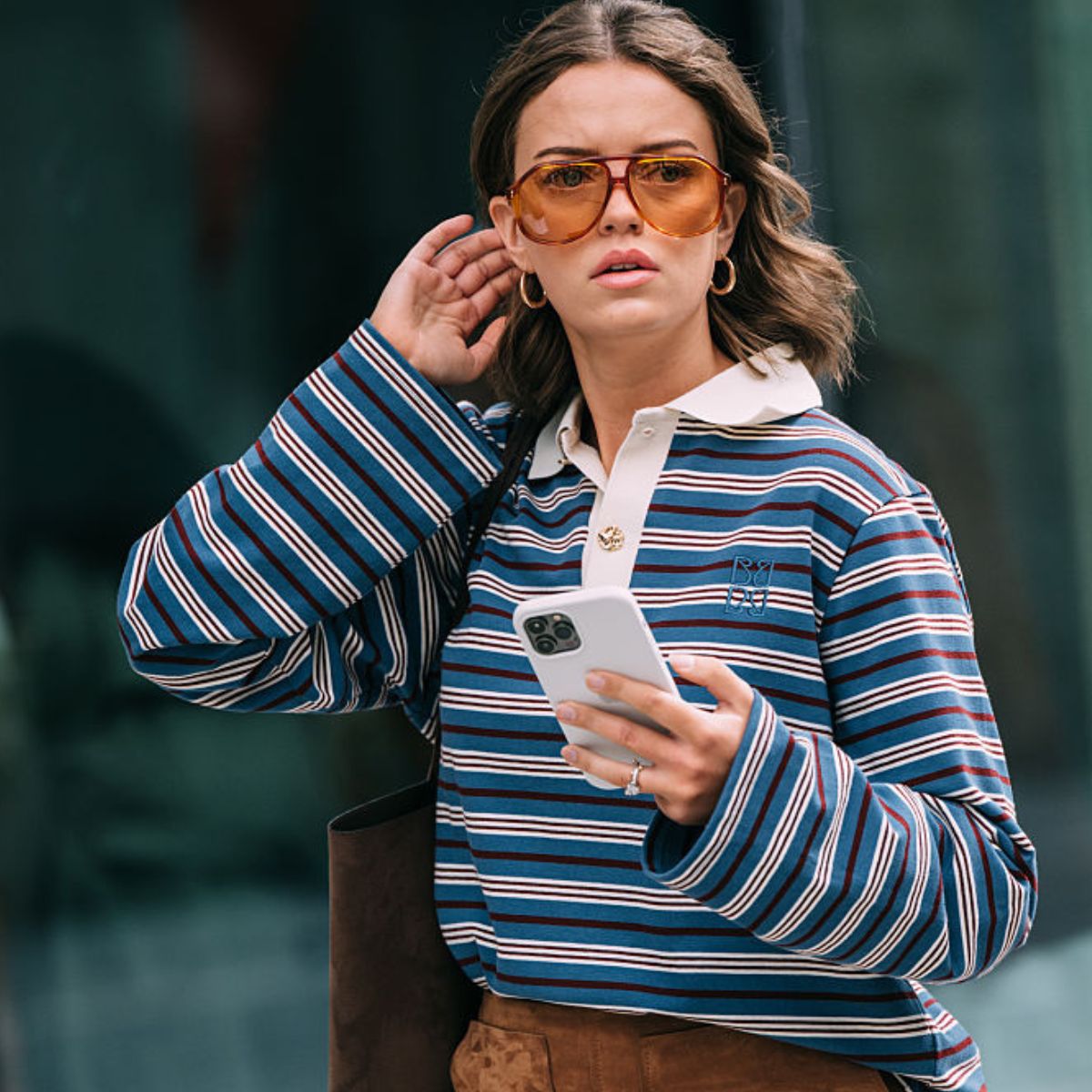 A woman wears a blue and white striped rugby shirt with tan-lens sunglasses