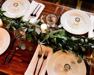 Thanksgiving centerpiece ideas with simple eucalyptus runner and white plates