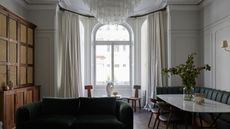 large living room with white walls, large bay window with arched glass and neutral curtains