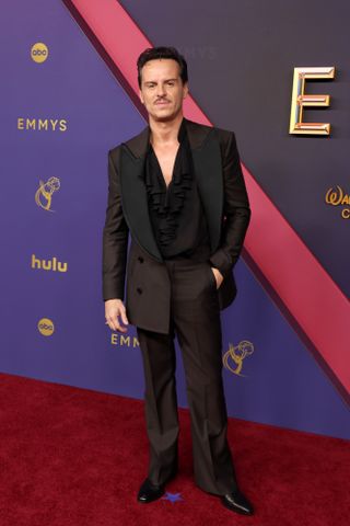 Andrew Scott wears a brown Vivienne Westwood suit with a black top and black shoes.