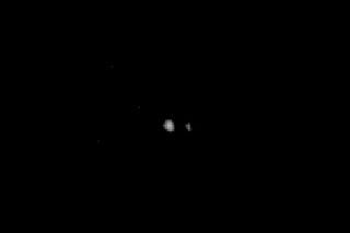 This photo of Pluto (center) and its largest moon Charon was captured by NASA's New Horizons spacecraft in July 2014 and released on Aug. 7. New Horizons took this image and others from a range of 267 million to 262 million miles (429 million to 422 million kilometers).