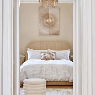 Elegant bed with cream walls and chandelier