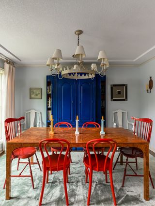 A royal blue cabinet stands out against a grey wall and rug