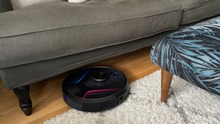 The Eufy RoboVac X8 cleaning a rug on a hard floor surrounded by furniture