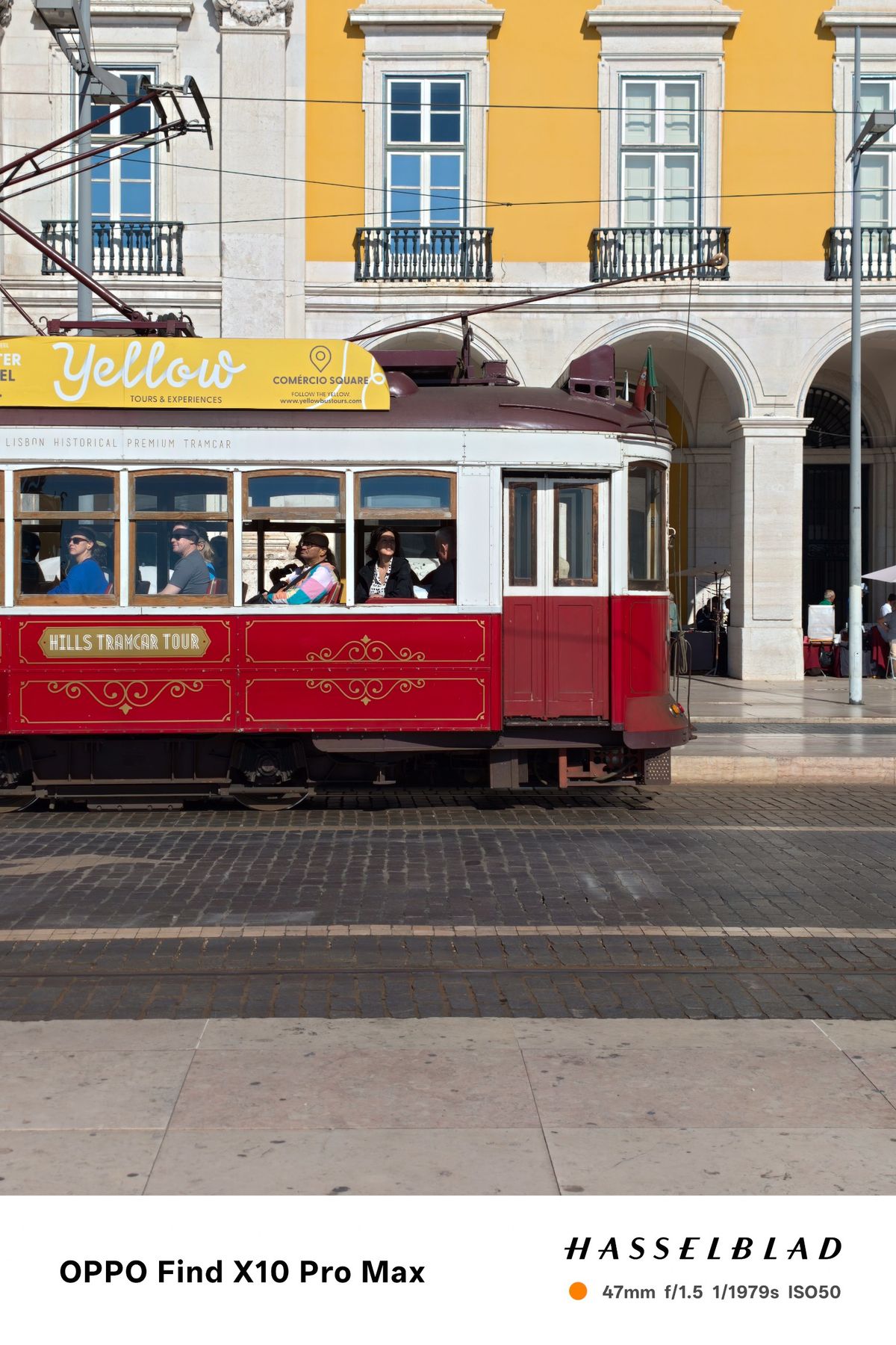 Red vintage tram passing yellow and white buildings in Lisbon.