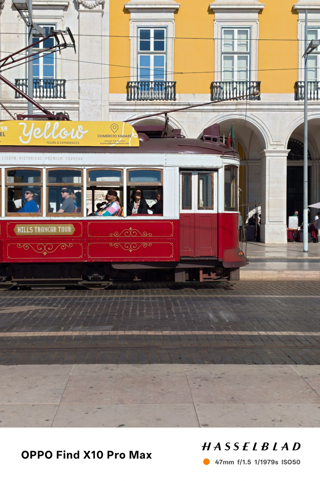 Red vintage tram passing yellow and white buildings in Lisbon.