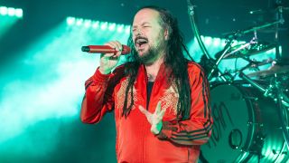 Jonathan Davis in a red ADIDAS jacket singing on stage