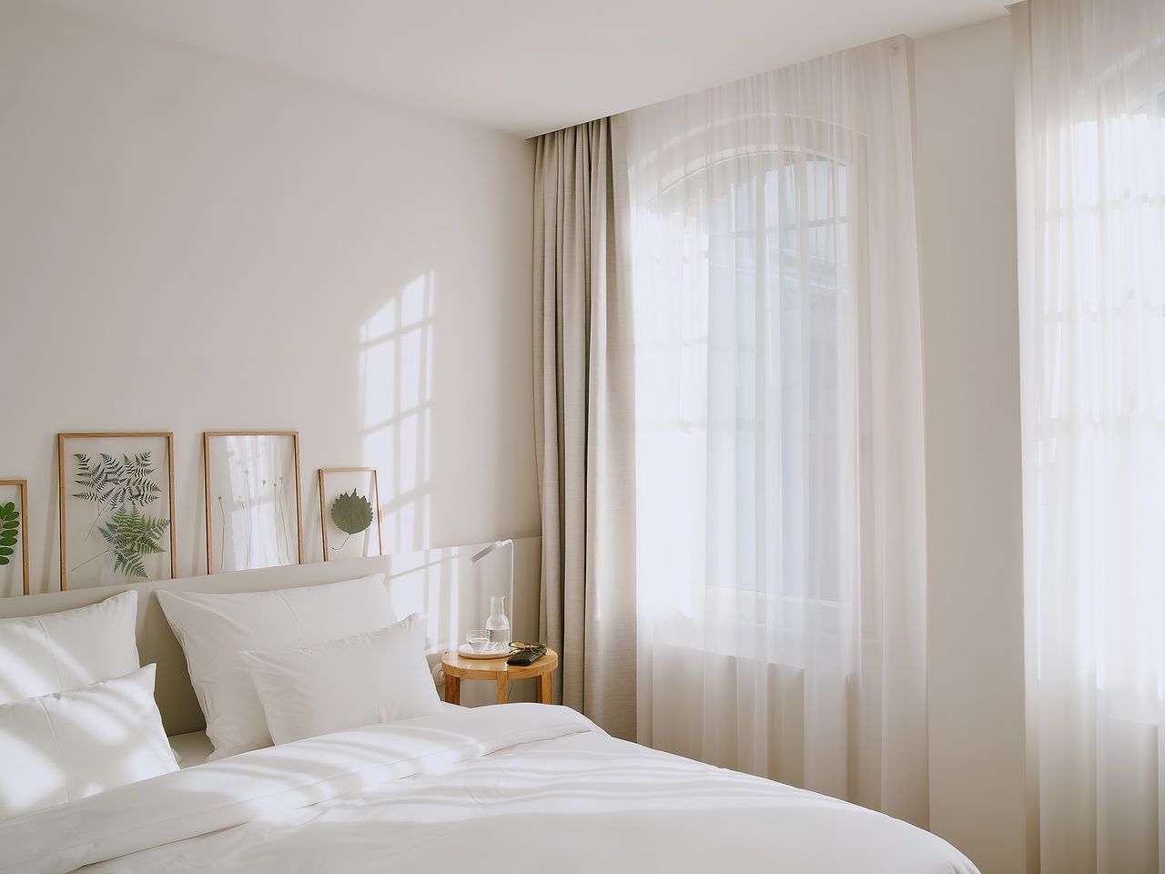 white bed with cream curtain and framed artwork