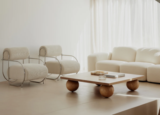 A minimalist living room with white furniture and a low-profile coffee table with oversized bun feet