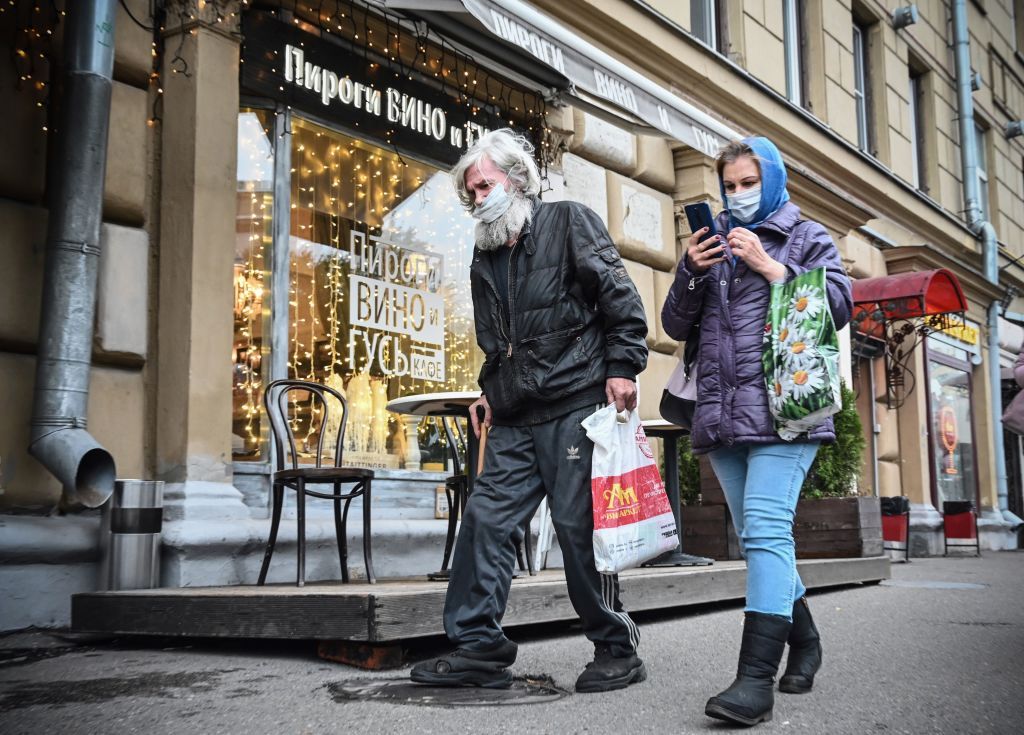 People wearing masks walk down a street in Moscow.