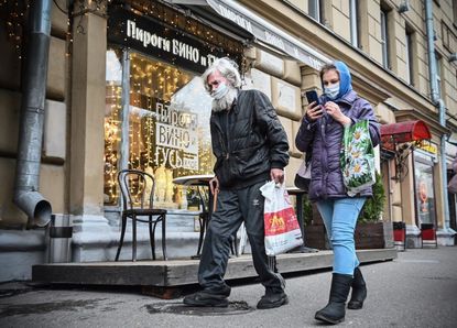 People wearing masks walk down a street in Moscow.