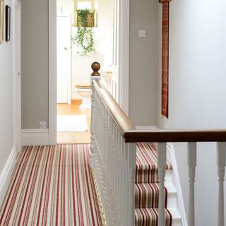 Upstairs hallway with white banisters and striped carpet