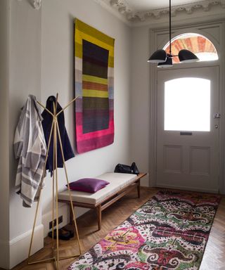 Grey hallway with statement patterned runner and colourful wall hanging