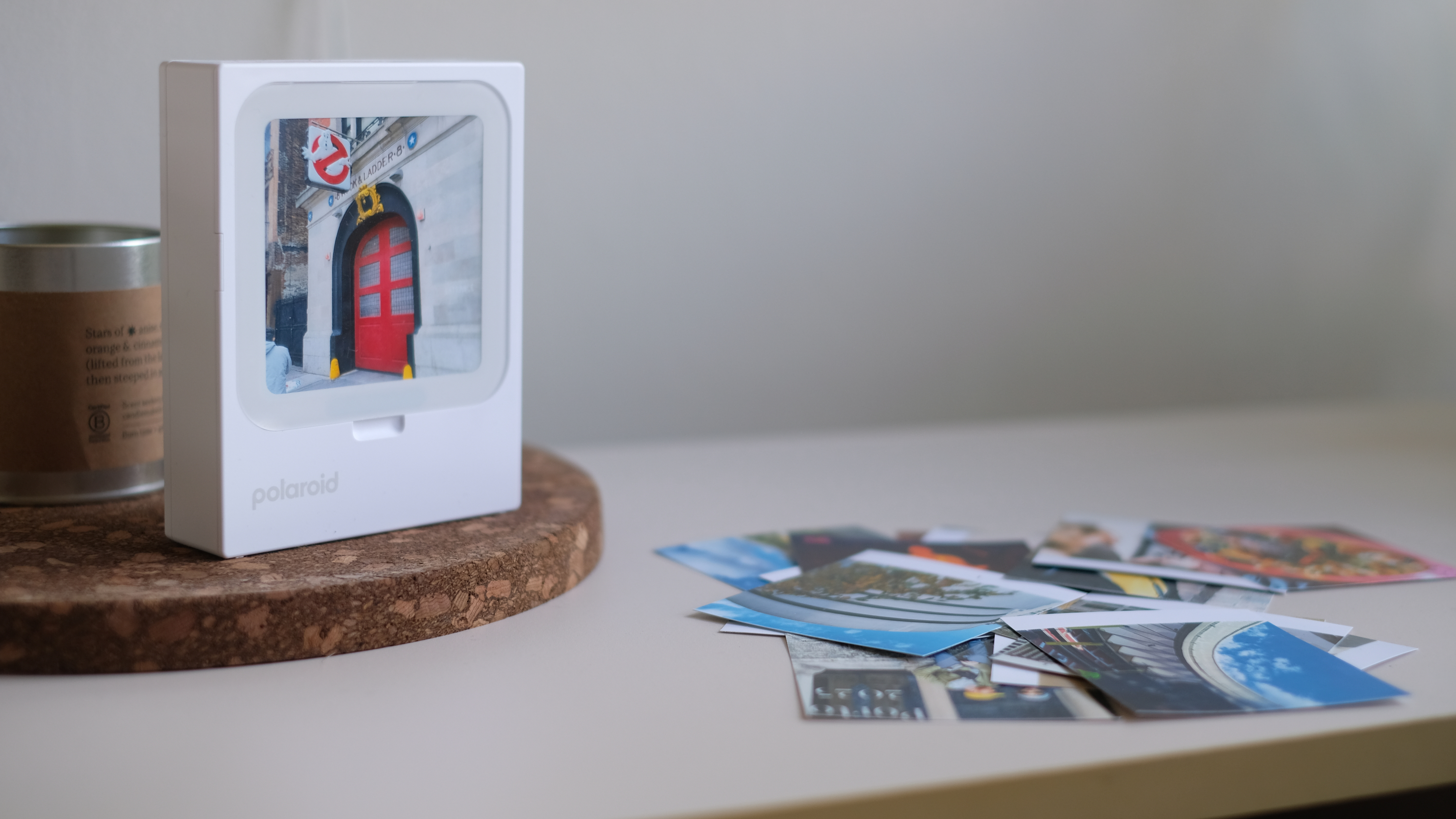 Photograph of Polaroid Hi-Print 3x3 mini instant printer displaying a photo of Ghostbusters headquarters, with other prints visible on the surface