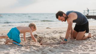 Man and son digging hole at beach