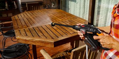 Worx pressure washer being used on wooden table outsdide 