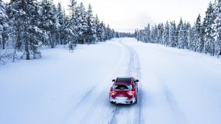 Car driving on mountain road in a snowy forest 