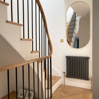 curved staircase with mirror and black radiator